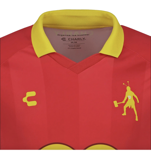 Close-up of a red soccer jersey with a yellow collar. It features a yellow silhouette of El Chapulín Colorado holding a mallet and the Charly brand logo on the chest.