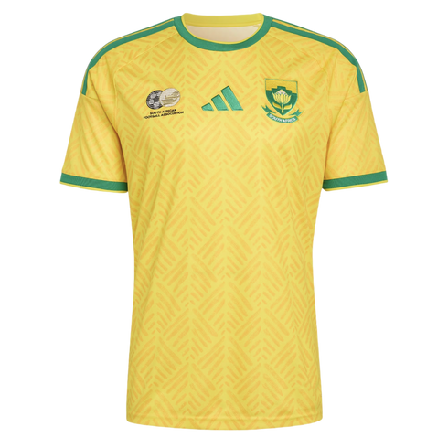Yellow Adidas South Africa national football team jersey with green trim on the collar, sleeves, and shoulders, featuring team crests on the chest over a tonal chevron pattern.