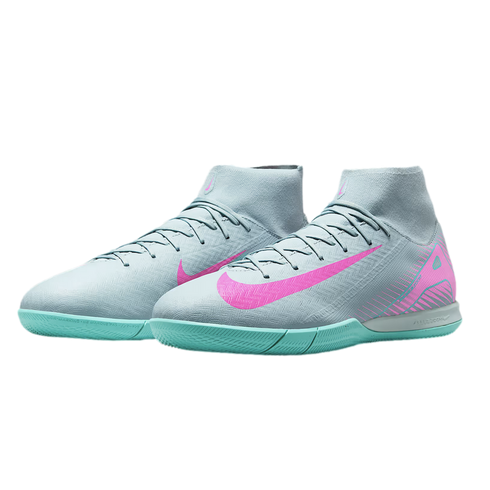 Light grey Nike indoor soccer shoes with turquoise soles and bright pink swooshes. Features a high-top sock collar and textured upper.