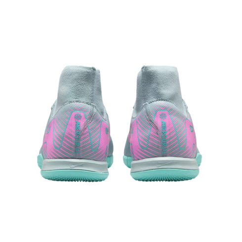 Rear view of two grey Nike Mercurial indoor soccer shoes with pink patterned heels and bright teal outsoles.