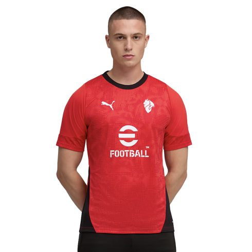 Man in a red Puma soccer jersey with white eFootball and Puma logos, featuring a black collar and side panels, against a black background.