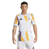 A model wearing a Real Madrid pre-match jersey and white shorts against a black background. The white shirt features a bold, jagged abstract pattern in yellow, grey, and light blue, with the black Adidas logo and Real Madrid club crest on the chest.