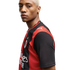 A blonde man wearing a red and black AC Milan soccer jersey with a Puma logo, looking at the camera against a white background.