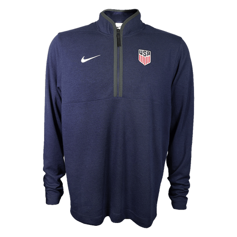 Dark blue long-sleeve Nike quarter-zip pullover with a white swoosh and USA Soccer crest, shown on a solid green background.