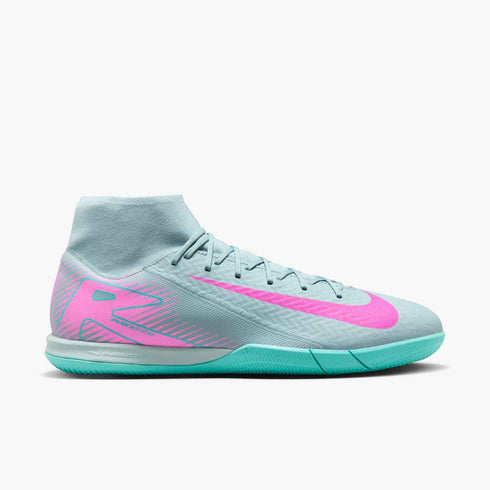 Light blue Nike indoor soccer shoe with a pink swoosh, pink heel graphics, and a bright teal sole. Features a mid-cut collar and "AIR ZOOM" technology.